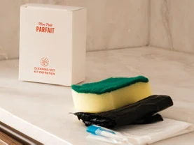 Boîte du kit entretien avec l'éponge, les sacs poubelle et les pastilles posés à côté
